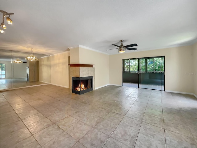 unfurnished living room with ceiling fan with notable chandelier, ornamental molding, light tile patterned floors, and a fireplace