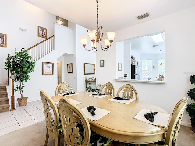 dining space with a chandelier, a skylight, and light carpet