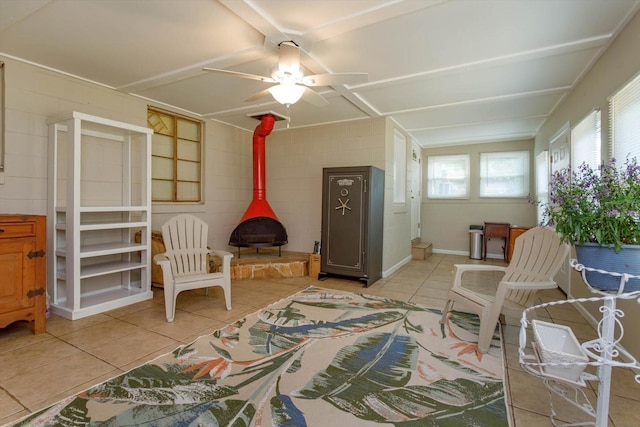 interior space with a wood stove, ceiling fan, and light tile floors