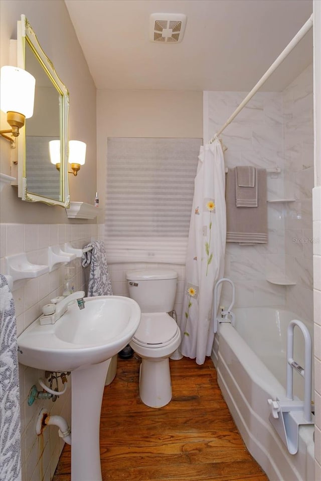 bathroom with shower / bathtub combination with curtain, hardwood / wood-style flooring, tile walls, backsplash, and toilet