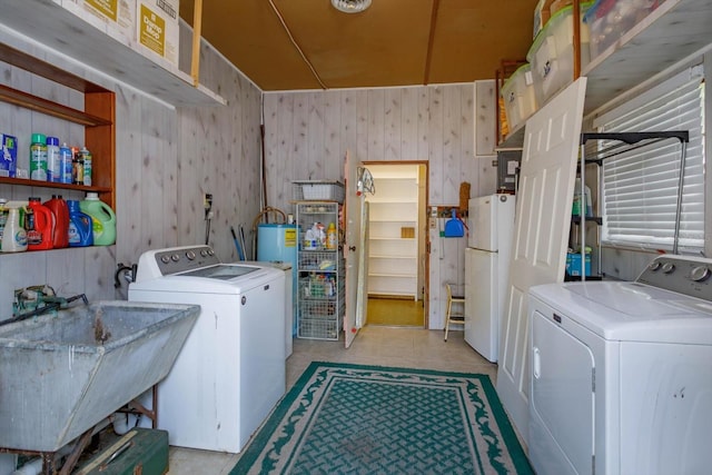 laundry area with sink, wooden walls, and washing machine and clothes dryer