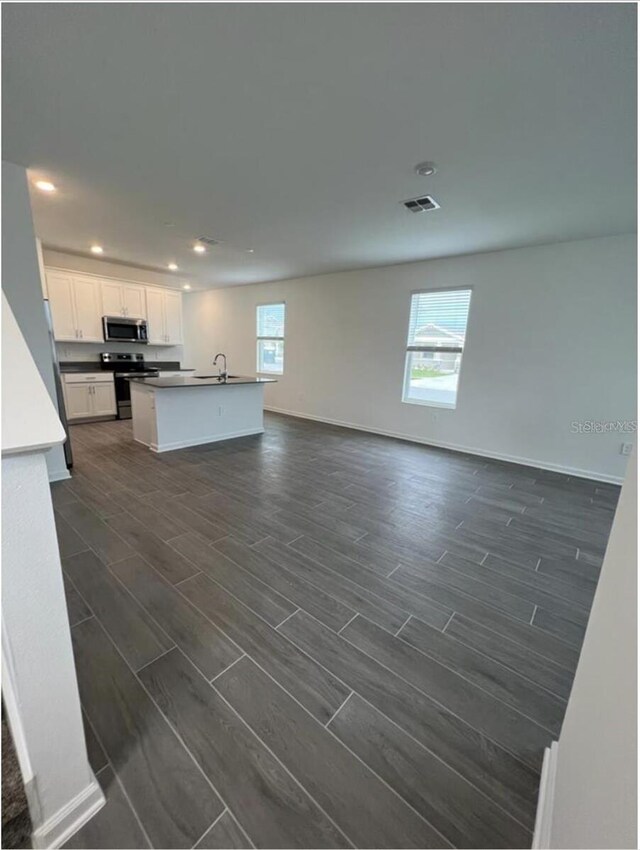 unfurnished living room with plenty of natural light, sink, and dark wood-type flooring