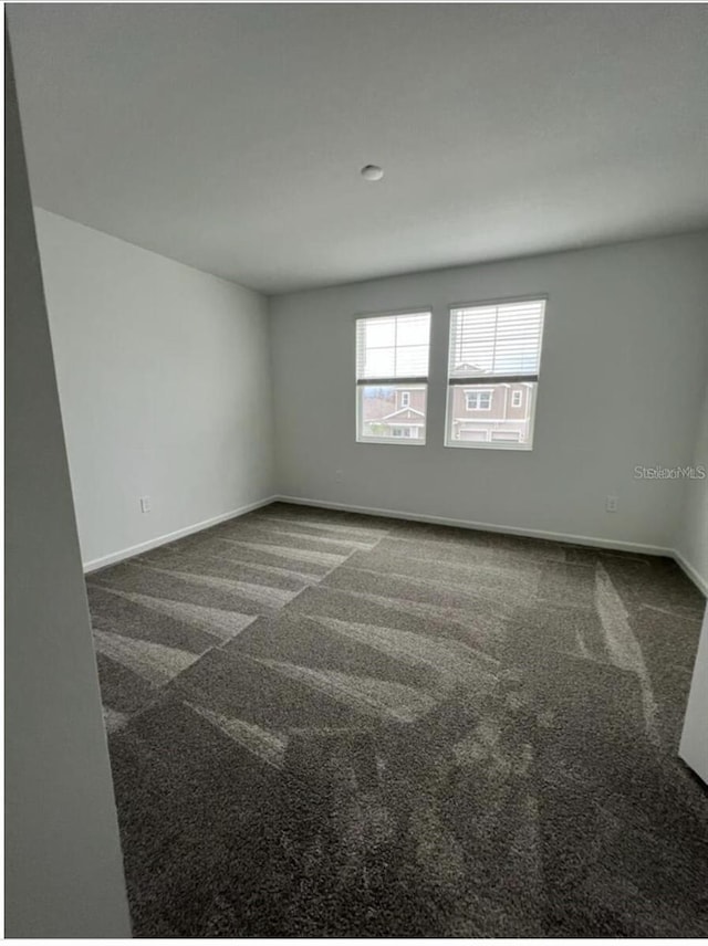 spare room with dark carpet