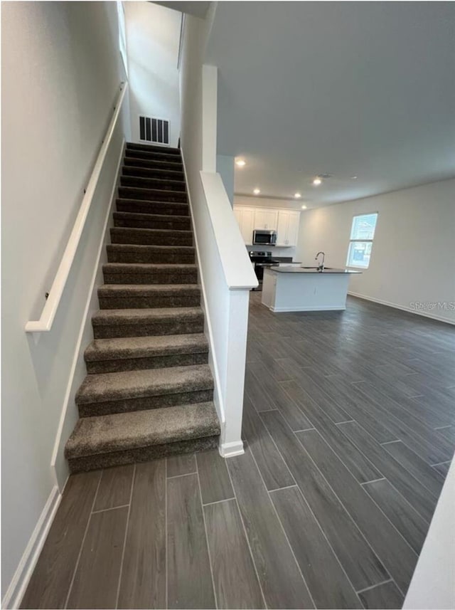 stairway featuring sink and dark hardwood / wood-style flooring