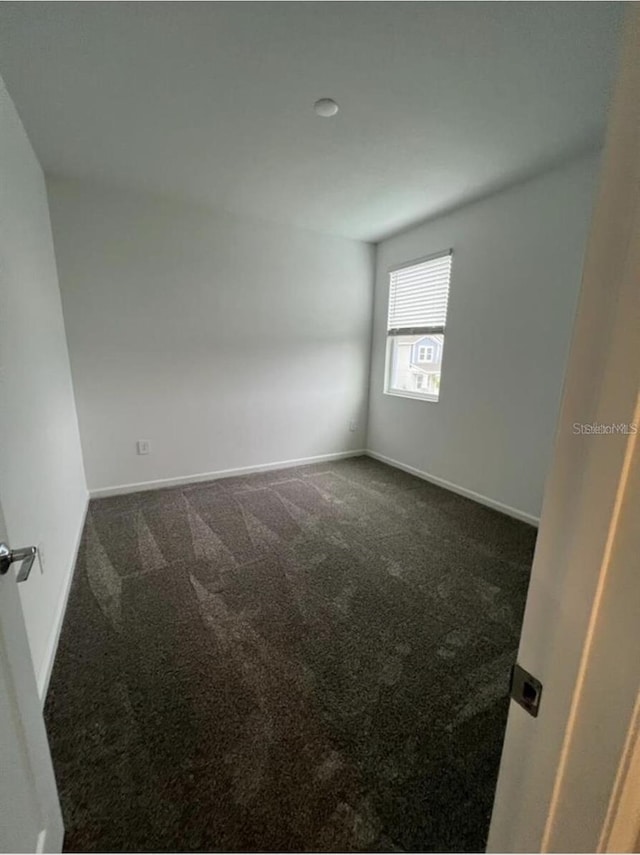 unfurnished room featuring dark carpet