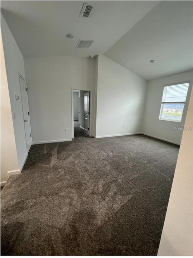 empty room featuring dark colored carpet and vaulted ceiling