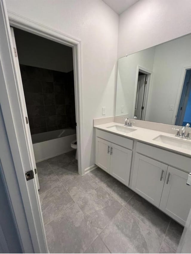 full bathroom with dual sinks, vanity with extensive cabinet space, tiled shower / bath, and tile flooring