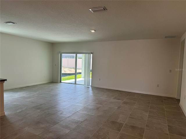 unfurnished room with a textured ceiling and tile floors