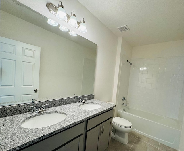 full bathroom featuring tile flooring, tiled shower / bath, a textured ceiling, toilet, and dual bowl vanity