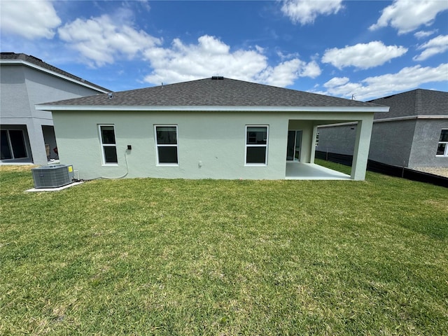 back of property with central AC, a lawn, and a patio area