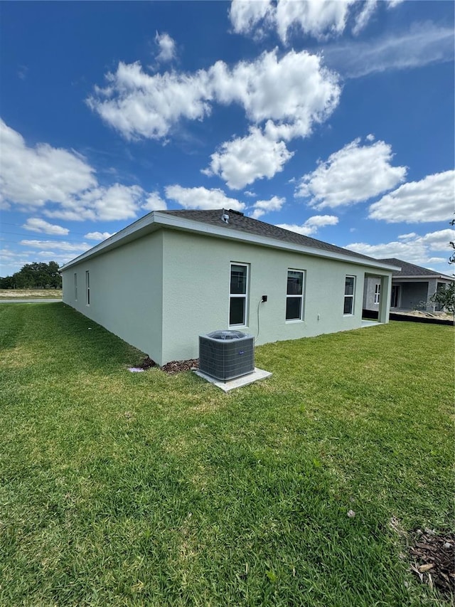 back of property featuring central air condition unit and a lawn