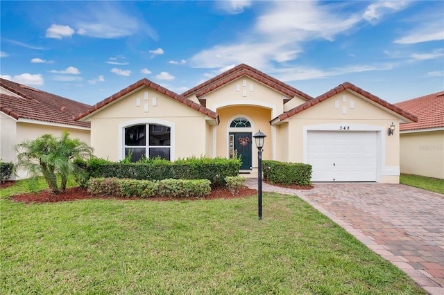 mediterranean / spanish home featuring a front yard and a garage