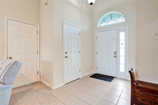 foyer entrance featuring light tile flooring and a towering ceiling