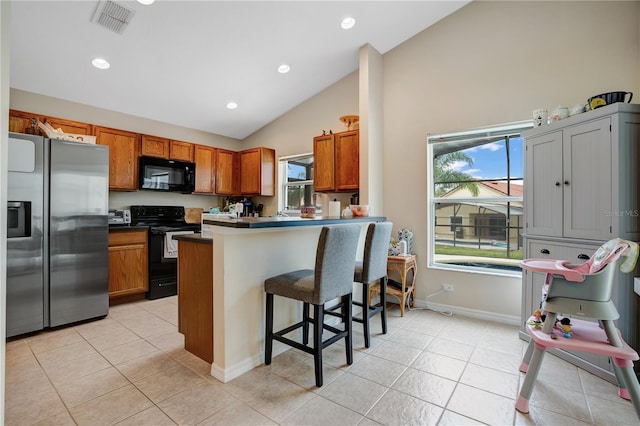 kitchen with high vaulted ceiling, kitchen peninsula, a breakfast bar area, black appliances, and light tile floors