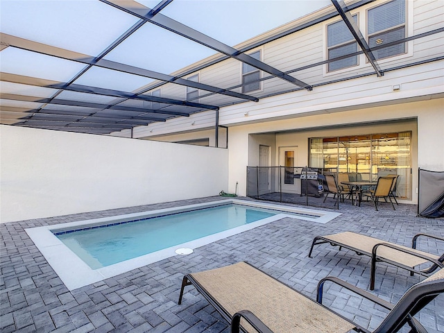 view of pool with glass enclosure and a patio area