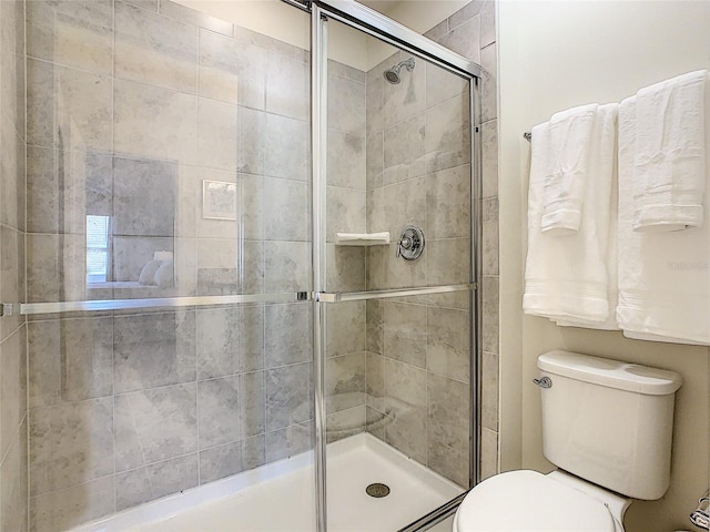 bathroom with a shower with door and toilet