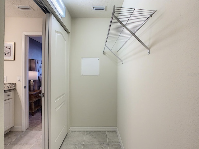 walk in closet with light tile floors