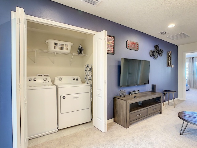 washroom with a textured ceiling, independent washer and dryer, light carpet, and washer hookup