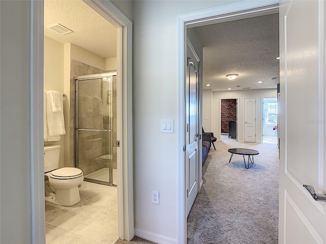 hallway with light colored carpet and a textured ceiling