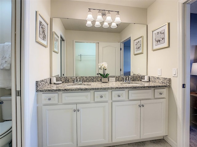 bathroom featuring toilet and dual vanity