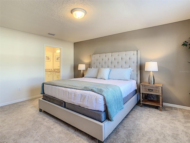 carpeted bedroom featuring ensuite bath and a textured ceiling