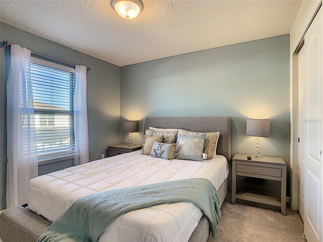 carpeted bedroom with a closet and a textured ceiling