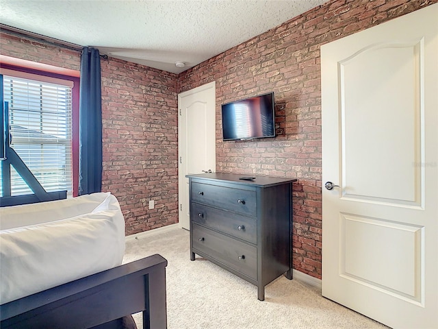 bedroom featuring a textured ceiling, light carpet, and brick wall