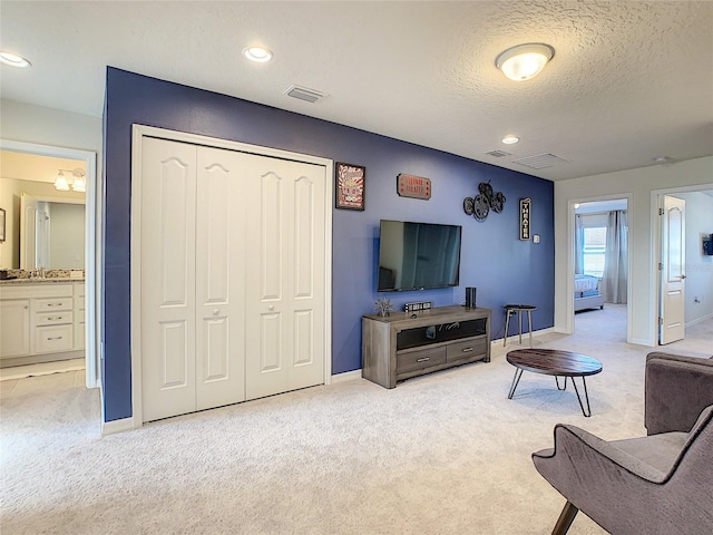 carpeted living room featuring a textured ceiling and sink