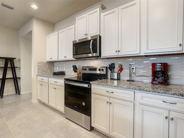 kitchen featuring backsplash, light tile floors, stainless steel appliances, and light stone countertops