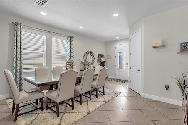 dining space with a textured ceiling and light tile flooring