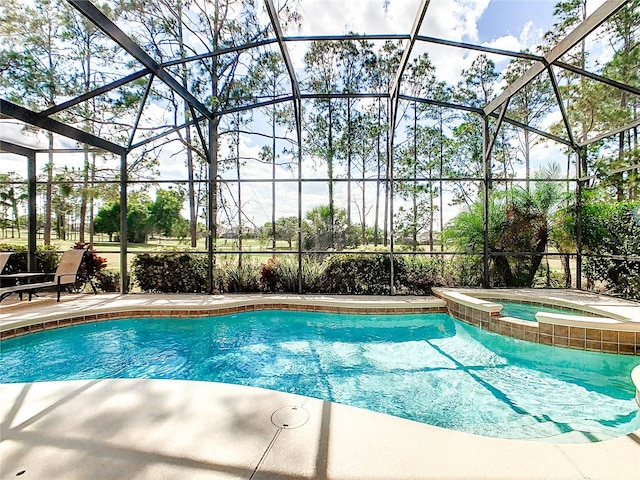 view of swimming pool featuring an in ground hot tub and glass enclosure