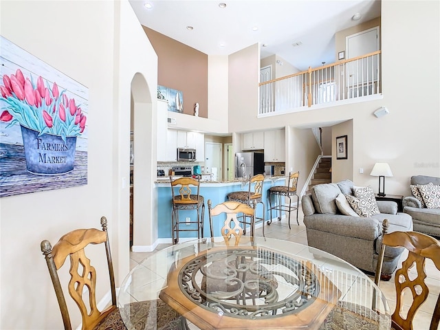 living room featuring a towering ceiling and light tile floors