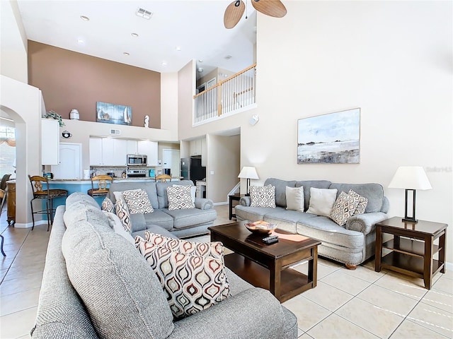 tiled living room featuring ceiling fan and a towering ceiling