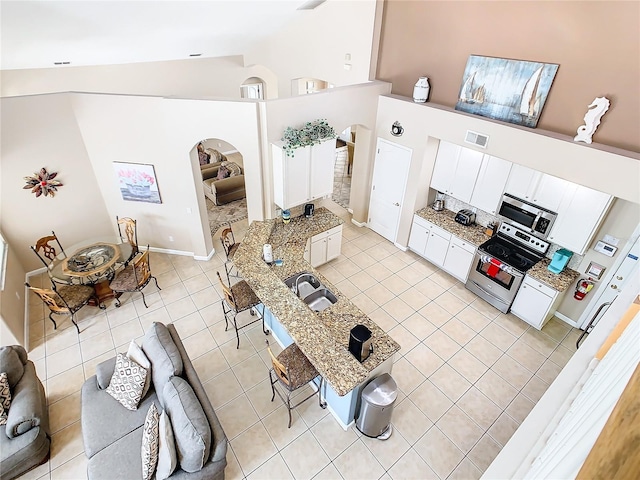 living room with sink, high vaulted ceiling, and light tile floors