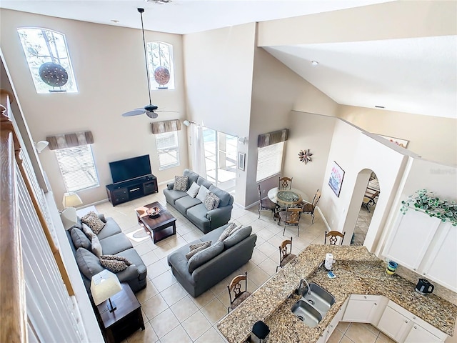 living room with a wealth of natural light, ceiling fan, and high vaulted ceiling