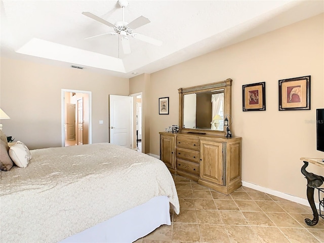 bedroom with a tray ceiling, ensuite bath, ceiling fan, and tile floors