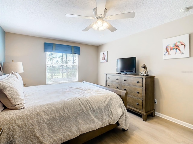 bedroom with light hardwood / wood-style floors, ceiling fan, and a textured ceiling