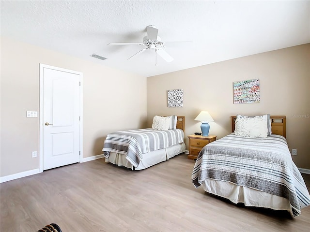 bedroom with a textured ceiling, ceiling fan, and hardwood / wood-style flooring