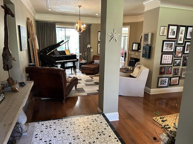 living room featuring a fireplace, crown molding, a chandelier, hardwood / wood-style flooring, and a textured ceiling