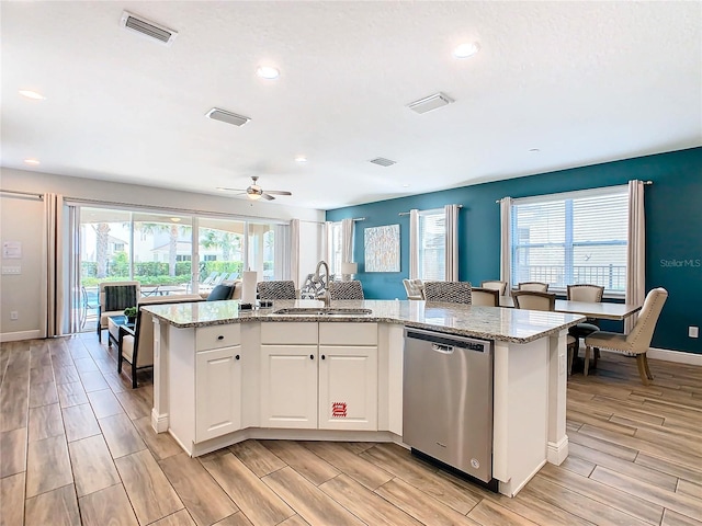 kitchen featuring light stone countertops, dishwasher, an island with sink, white cabinetry, and sink