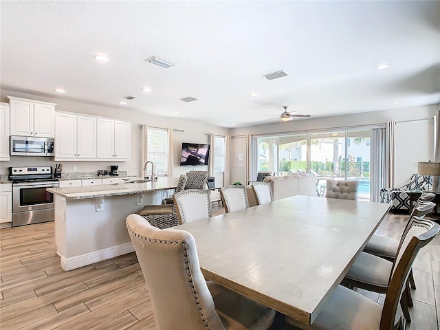 dining room with a wealth of natural light, ceiling fan, light hardwood / wood-style floors, and sink