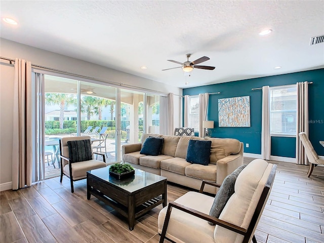 living room with a healthy amount of sunlight, a textured ceiling, ceiling fan, and hardwood / wood-style flooring