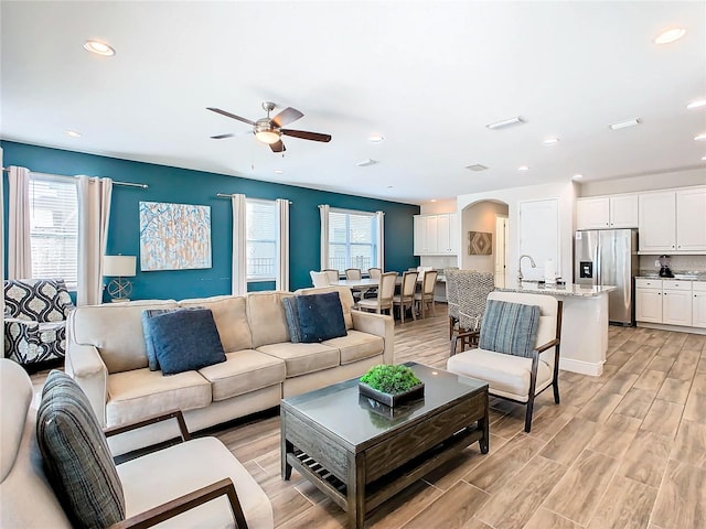 living room featuring plenty of natural light, sink, ceiling fan, and light wood-type flooring