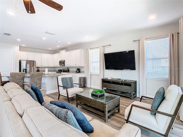 living room featuring light hardwood / wood-style floors and ceiling fan