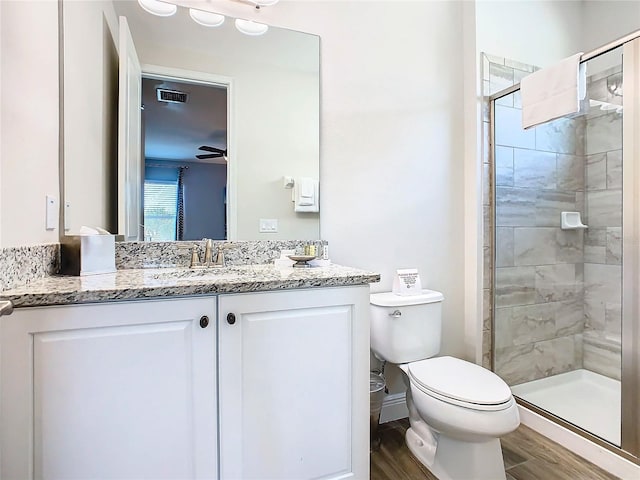 bathroom with a shower with shower door, ceiling fan, toilet, wood-type flooring, and vanity