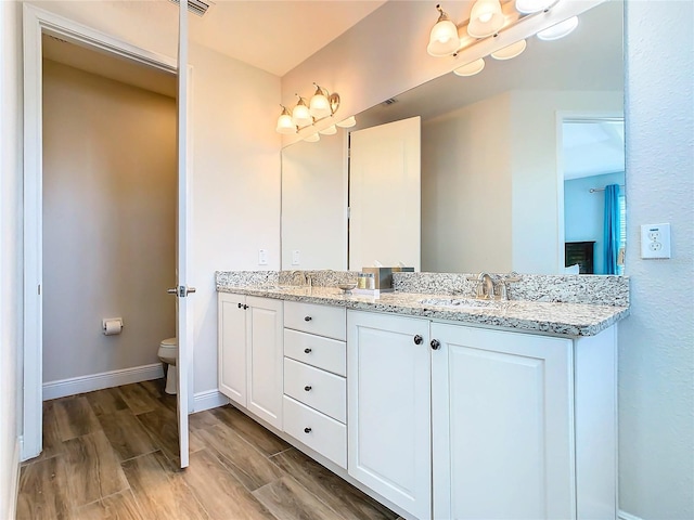 bathroom featuring hardwood / wood-style floors, dual bowl vanity, and toilet