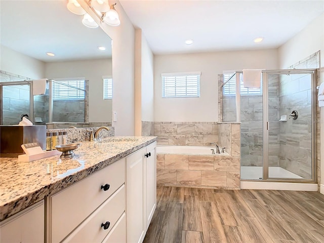 bathroom featuring a healthy amount of sunlight, hardwood / wood-style floors, vanity, and shower with separate bathtub