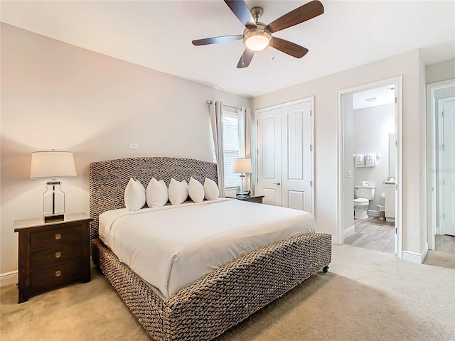 bedroom featuring light colored carpet, ceiling fan, a closet, and ensuite bathroom