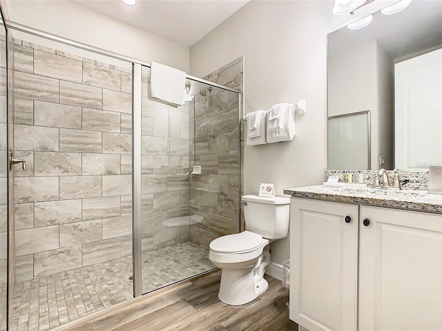 bathroom featuring walk in shower, hardwood / wood-style flooring, vanity, and toilet