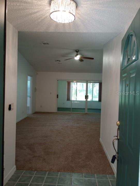 empty room featuring tile floors, a textured ceiling, and ceiling fan